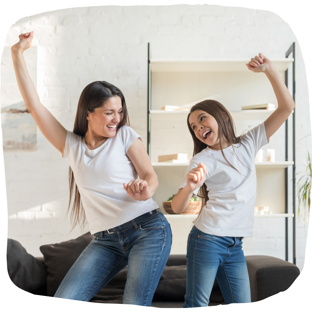 Mom and daughter dancing in living room in matching outfits smiling